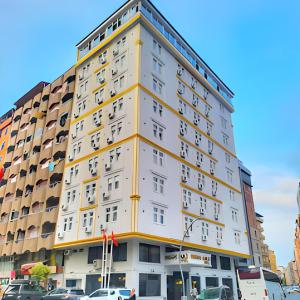 wysoki biały budynek z żółtym przycinaniem na ulicy miejskiej w obiekcie Rhisos Gold Otel w mieście Rize