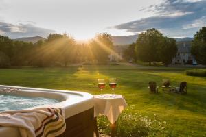 dos copas de vino sentadas en una mesa junto a una piscina en Brass Lantern Inn, en Stowe