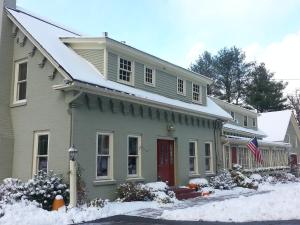 une maison avec une porte rouge dans la neige dans l'établissement Brass Lantern Inn, à Stowe