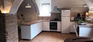 La cuisine est équipée de placards blancs et d'un réfrigérateur blanc. dans l'établissement Mas D'en Gregori, à Porrera