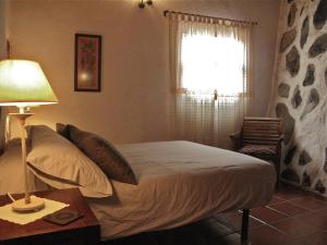 a bedroom with a bed and a lamp and a window at Casa Rural El Tabaibal in Hermigua