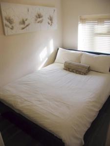 1 cama blanca en un dormitorio con ventana en Must see, Quality 1 bed, Romford, 20 mins C.London en Romford