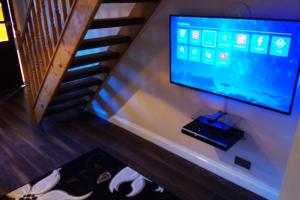 Must see, Quality 1 bed, Romford, 20 mins C.London في رومفورد: تلفزيون بشاشة مسطحة على جدار بجوار درج