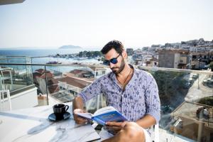 a man sitting at a table reading a book at Kali Thea Suites in Neos Marmaras