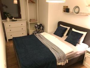 Erkel 19 Apartmanház في كيزتيلي: غرفة نوم مع سرير ووسائد زرقاء ومرآة
