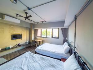 a hotel room with two beds and a tv at Tra旅宿 in Taichung