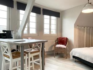 een kamer met een tafel, stoelen en ramen bij Mon Port d'Attache in Port-en-Bessin-Huppain