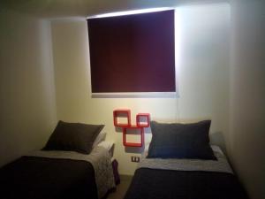 Cette chambre comprend deux lits et une grande fenêtre. dans l'établissement Departamento Resort Laguna del Mar, à La Serena