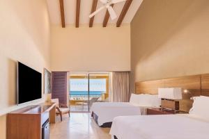um quarto de hotel com duas camas e uma televisão em Grand Fiesta Americana Los Cabos All Inclusive Golf & Spa em Cabo San Lucas