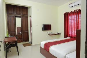 a bedroom with a bed and a desk and a television at BLUEWAY RESIDENCY BUSINESS BOUTIQUE HOTEL in Trivandrum