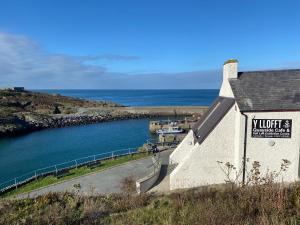 a building with a sign on it next to a body of water at Royal Oak Cottage in Amlwch