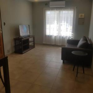 een woonkamer met een bank en een televisie bij Hécate in San Fernando del Valle de Catamarca