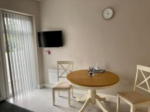 una mesa y sillas en una habitación con un reloj en la pared en Erne Getaway No.6 Brand new 1 bed apartment en Enniskillen