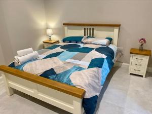 a bedroom with a bed with a blue and white comforter at Erne Getaway No.6 Brand new 1 bed apartment in Enniskillen