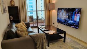 een woonkamer met een bank, een tafel en een tv bij Modern, Luxe & Spacious 4-Bed Condo, Full Kitchen, 3 Min walk to Beach, Tram & Marina By "La Buena Vida Holiday Homes" in Dubai