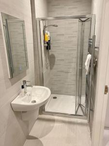 baño blanco con ducha y lavamanos en Erne Getaway No.7 Brand new 1 bed apartment, en Enniskillen