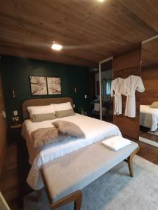 1 dormitorio con 1 cama grande y espejo en Vila Nambu - Exclusive Pousada, en Gramado