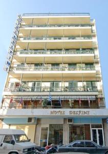 wysoki budynek z samochodami zaparkowanymi przed nim w obiekcie Delfini Hotel w Pireusie