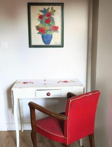 - un bureau avec une chaise rouge et un vase de fleurs dans l'établissement la dame jeanne, à Cucuron