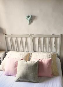 Una cama blanca con almohadas rosas en un dormitorio en la dame jeanne en Cucuron