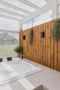 a bathroom with a white tub and a wooden wall at Vila Nambu - Exclusive Pousada in Gramado