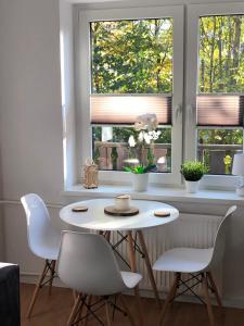 Apartament 4 osobowy في زاكوباني: طاولة بيضاء وكراسي في غرفة بها نافذتين