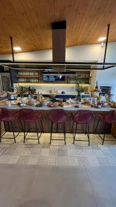 a kitchen with a long counter with chairs and food on it at Vila Nambu - Exclusive Pousada in Gramado