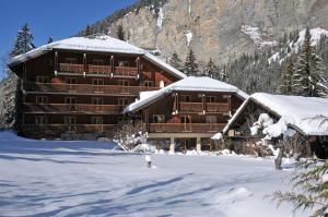 een groot houten gebouw met sneeuw op de grond bij Hotel Les Lans in Morzine