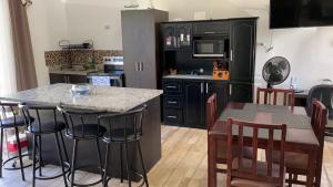 a kitchen with black cabinets and a table with bar stools at Casa Linda in Uvita