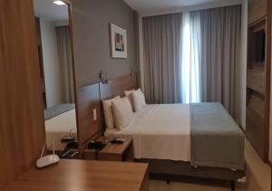 Quality Hotel & Suites Brasília في برازيليا: غرفة فندقية بسرير كبير ونافذة