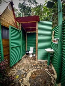 a green bathroom with a toilet and a sink at ECO Cabin - TANOA Minca in Minca