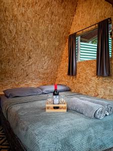 1 dormitorio con 1 botella de vino en la cama en ECO Cabin - TANOA Minca, en Minca