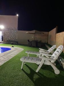 - un groupe de chaises longues assises à côté de la piscine la nuit dans l'établissement Fog Mountain Hotel Rooms & sauna, 