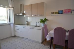 a kitchen with white cabinets and a table with purple chairs at Apartments Pavicic Marija in Pag