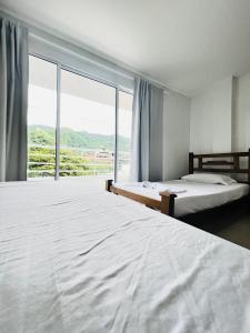 a bedroom with two beds and a large window at Hostal Taganga Plaza in Taganga