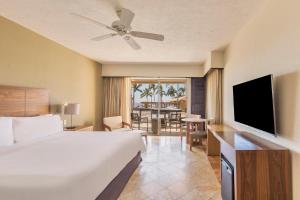 une chambre d'hôtel avec un lit, une télévision et une table dans l'établissement Grand Fiesta Americana Los Cabos All Inclusive Golf & Spa, à Cabo San Lucas