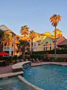 a swimming pool in front of a house with palm trees at The Dawn on Galveston Beach in Galveston