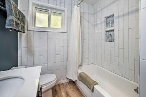 ein weißes Badezimmer mit Badewanne und Toilette in der Unterkunft Secluded Suttons Bay Retreat with Fire Pit! in Suttons Bay + 29 Fotos