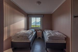 two beds in a room with a window at PederStua in Storeidet