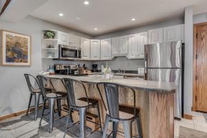 a kitchen with white cabinets and a large island with bar stools at Laurelwood Condominiums 202 in Snowmass Village