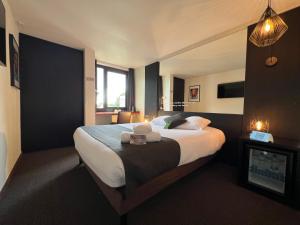 een hotelkamer met een groot bed en een open haard bij Logis Hôtel Restaurant Des Acacias Lille Tourcoing in Neuville-en-Ferrain