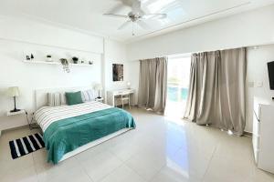 1 dormitorio blanco con 1 cama y ventilador de techo en Elegante Blue Marine Apartamento Juan Dolio, en Juan Dolio