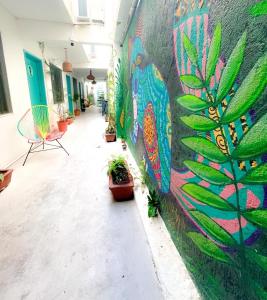 une fresque murale dans un couloir orné de plantes dans l'établissement Casa Cálido Hotel, à Cozumel