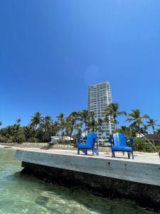 two blue chairs sitting on a dock near the water at Aquarella Beachfront 2BR Sunset Juan Dolio in La Puntica de Juan Dolio