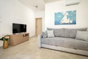 a living room with a couch and a tv at Zora Residence in Kaštela