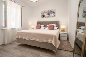 a white bedroom with a large bed with a mirror at Zora Residence in Kaštela