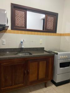 a kitchen with a sink and a stove and a mirror at Apartamento Pimenta Rosa, 400m do mar, rua principal in Imbassai