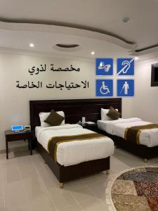 two beds in a room with signs on the wall at Arrawiya Alzahabia Hotel in Dammam