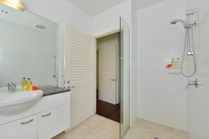 a white bathroom with a sink and a shower at Villa Frangipani in Port Douglas