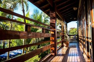 a porch of a house with a fence and palm trees at Vila Juquehy Lofts & Suítes in Juquei